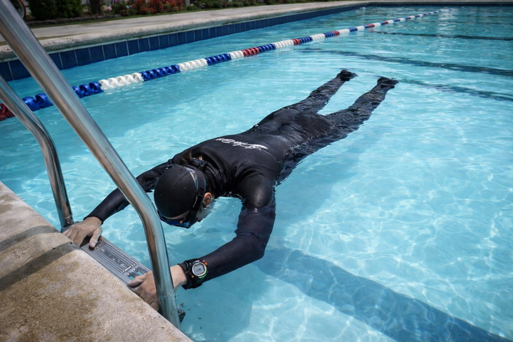 غواص يرتدي بدلة غوص حر يطفو بثبات تحت سطح الماء أثناء تمرين الأبنيا الساكنة