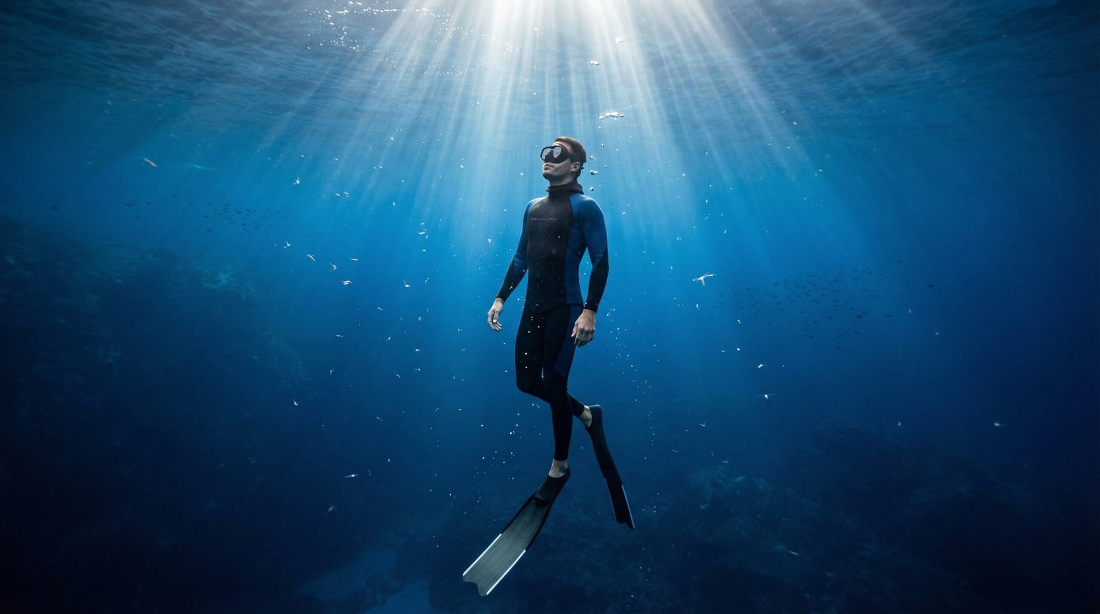 غواص حر يحبس أنفاسه بهدوء تحت الماء مع أشعة الشمس تخترق سطح البحر