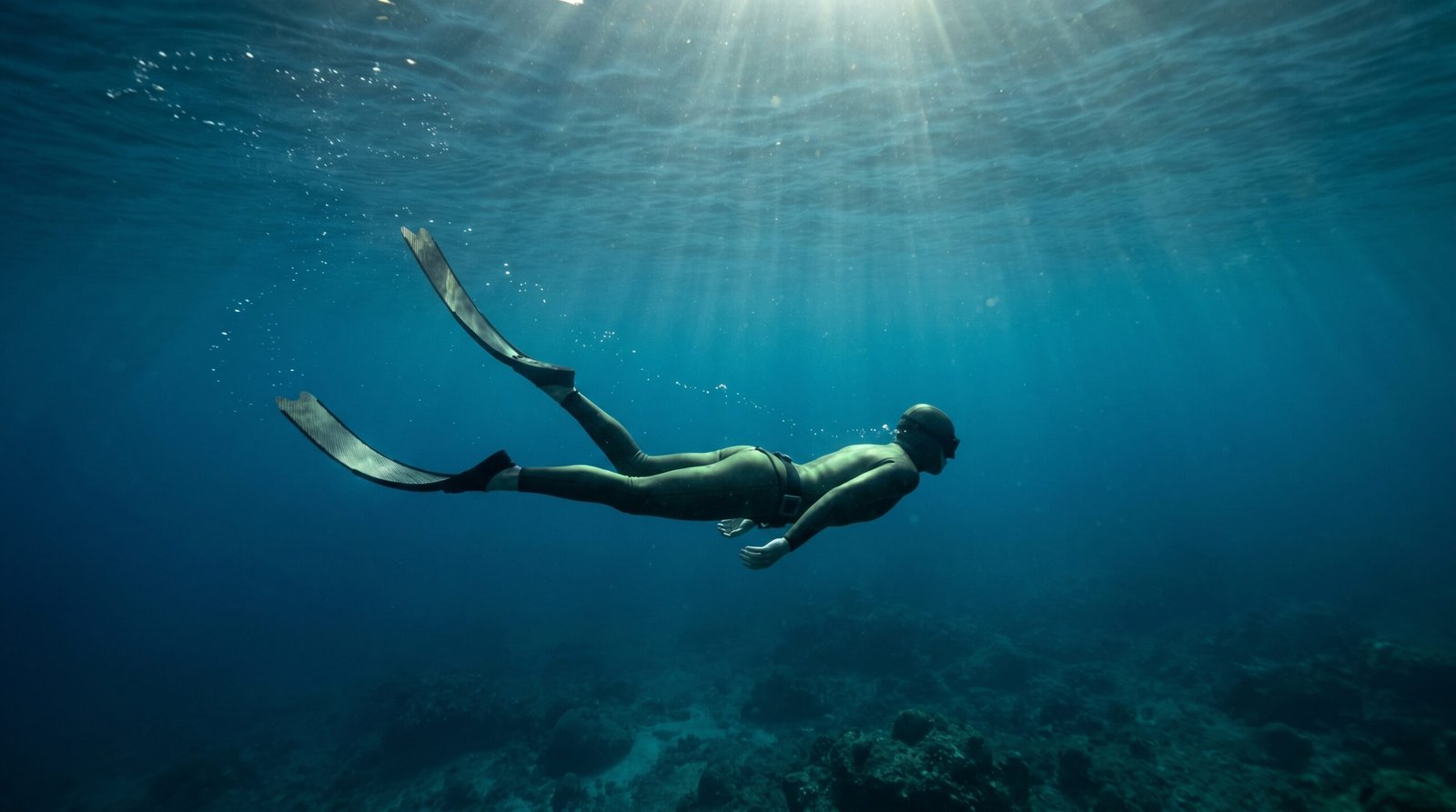 غواص حر يسبح تحت الماء بحركة هادئة مع زعانف طويلة أثناء حبس النفس