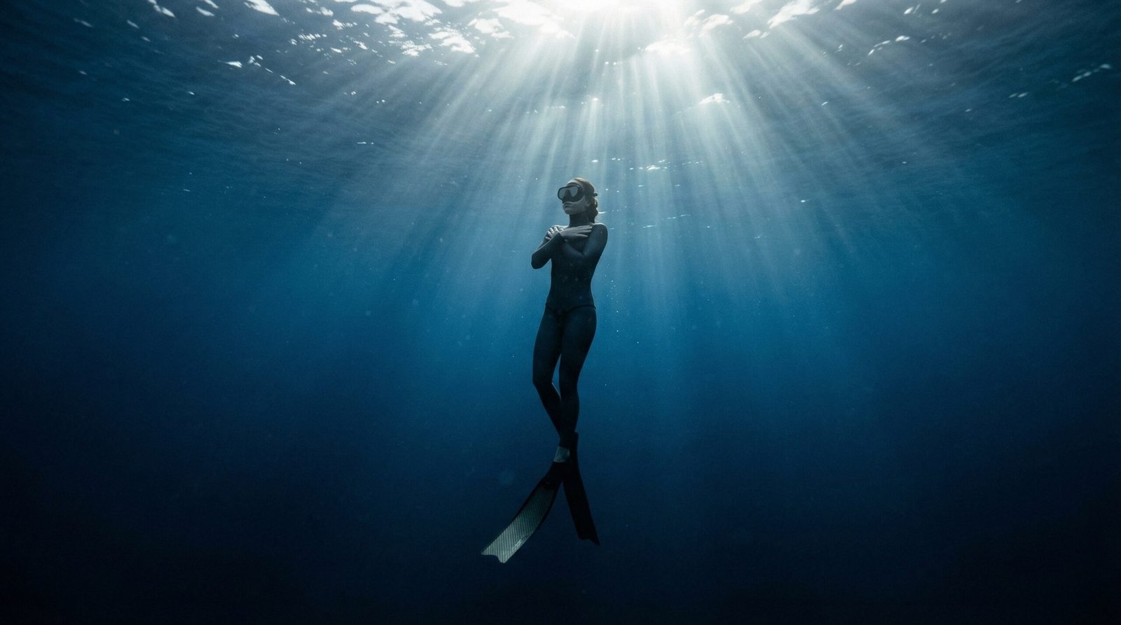 غواص حر يطفو بهدوء في عمق البحر أثناء حبس النفس